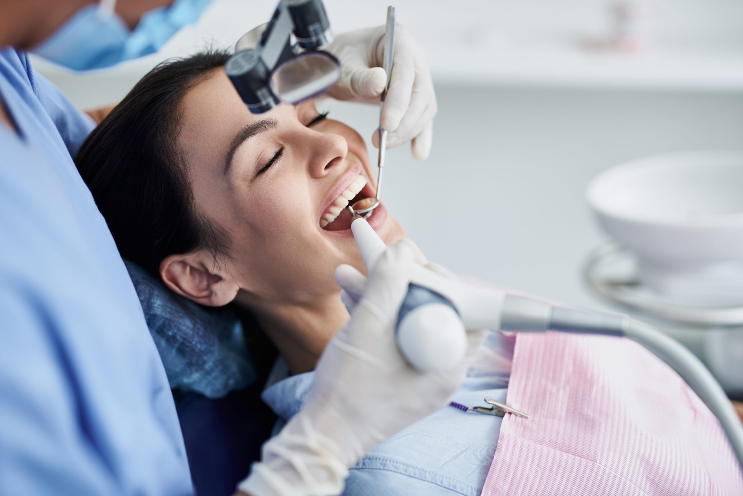 Young woman with closed eyes having dental procedure at clinic